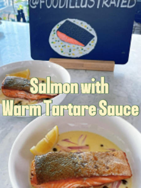 Pan-seared salmon with warm tartare sauce on a white plate, featuring crispy golden skin and a silky butter sauce studded with capers and fresh herbs.