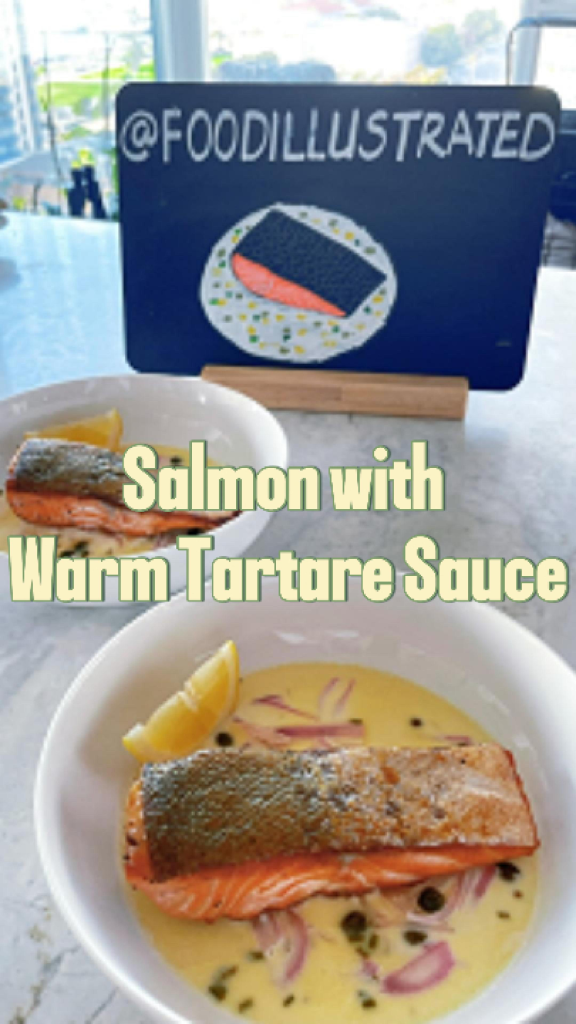 Pan-seared salmon with warm tartare sauce on a white plate, featuring crispy golden skin and a silky butter sauce studded with capers and fresh herbs.