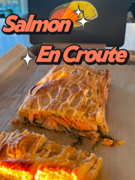Golden brown Ultimate Salmon en Croute sliced to reveal layers of flaky puff pastry, creamy spinach filling, and perfectly cooked salmon on a wooden board.