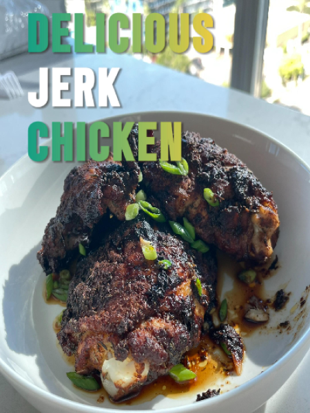Homemade jerk spice paste in a glass bowl and hands generously coating chicken legs with the aromatic seasoning mixture.