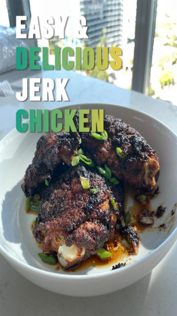 Homemade jerk spice paste in a glass bowl and hands generously coating chicken legs with the aromatic seasoning mixture.