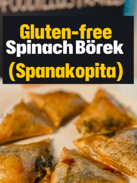 Golden-brown crispy gluten-free spinach börek triangles arranged on a wooden board with a small bowl of tzatziki and a fresh lemon wedge for dipping.