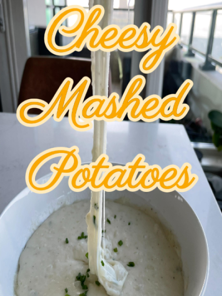 Close-up of a spoonful of creamy mozzarella mashed potatoes with long, stretchy cheese strands connecting the spoon to the bowl, garnished with chives.