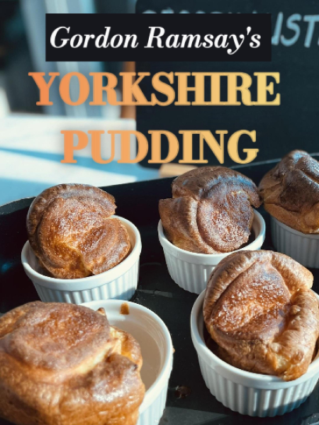 Tall, golden Yorkshire puddings baked in a muffin tin, crispy edges and fluffy centers, served on a wooden board with a small jug of gravy.