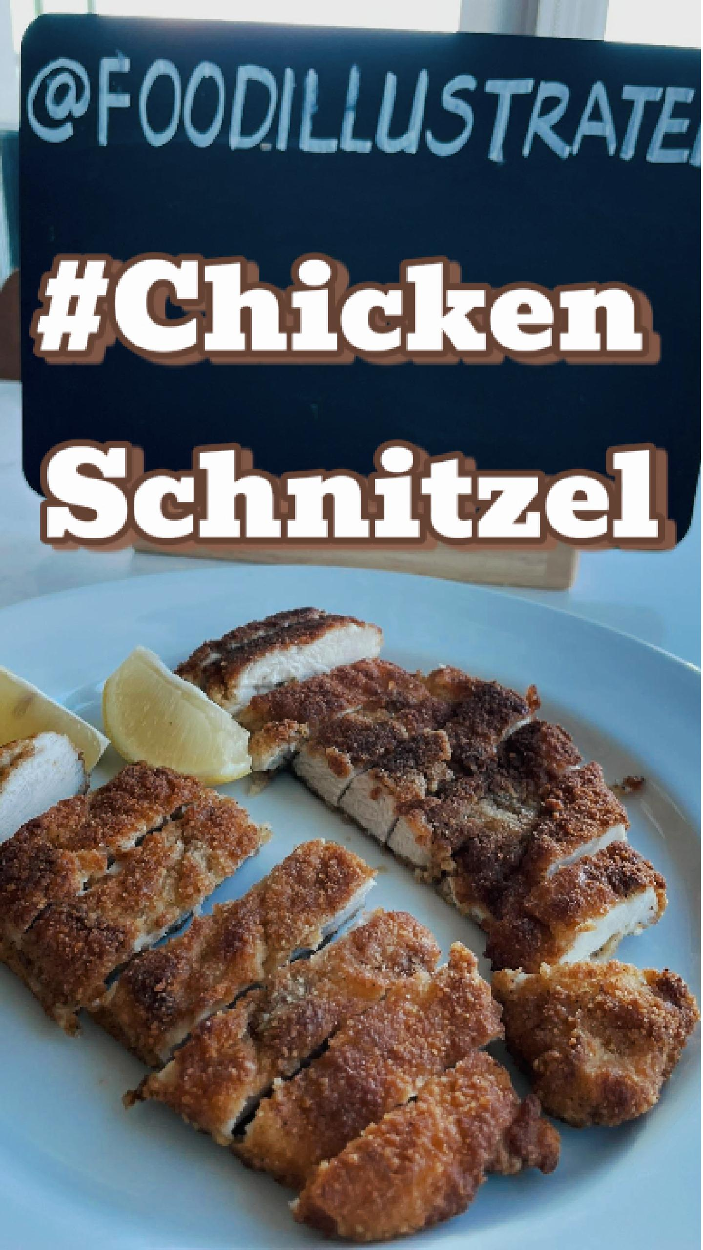 Golden brown crispy chicken schnitzel cutlets on a wire rack with lemon wedges and fresh parsley in a cast iron skillet.