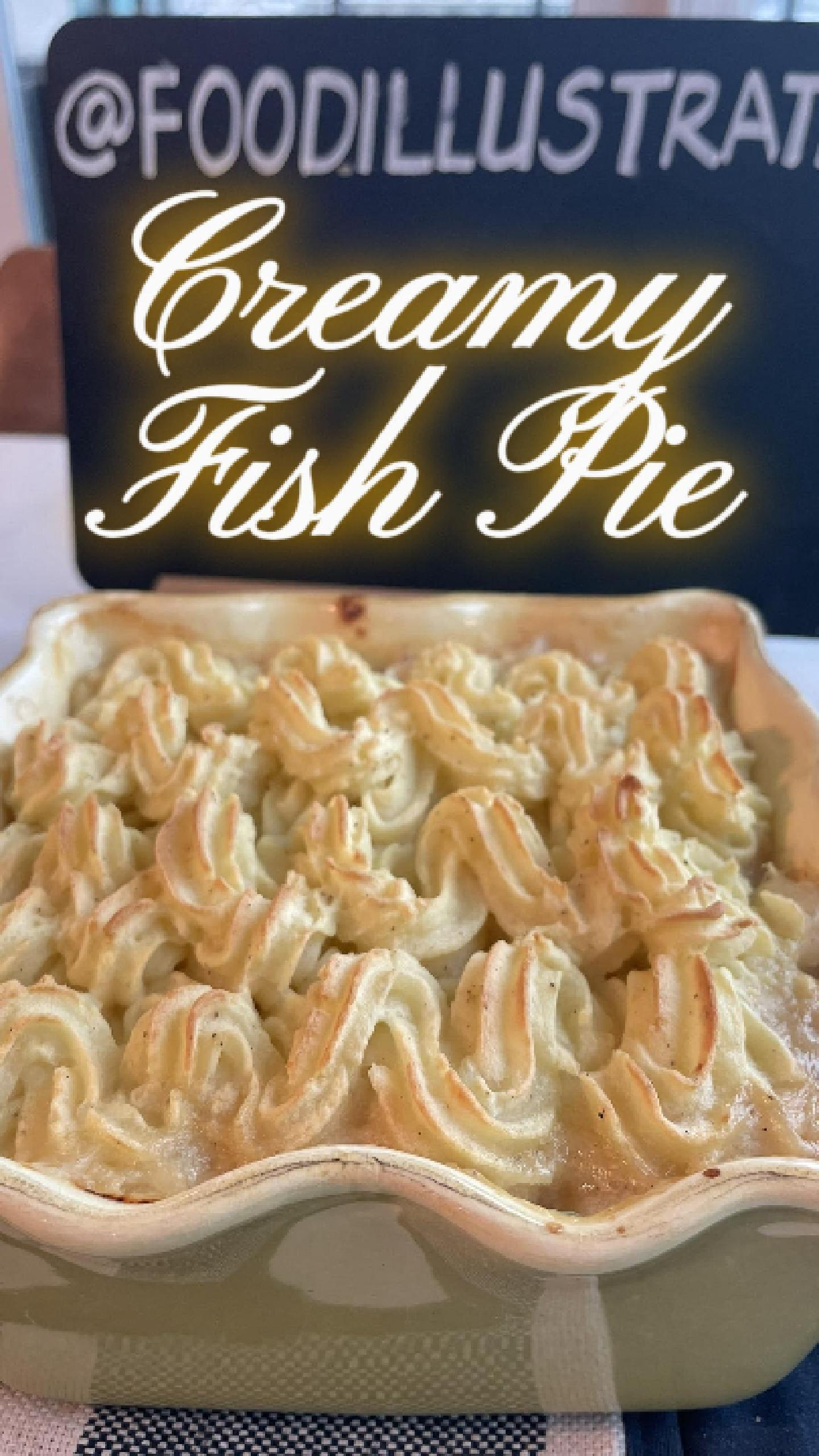 Golden brown Easy Creamy Fish Pie in a white baking dish served with a spoon, showing creamy filling with white fish, vegetables, and hard-boiled eggs.
