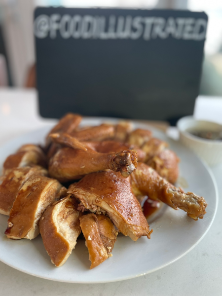 Glistening whole Cantonese Soy Sauce Chicken (豉油鸡) chopped into pieces, garnished with green onions and cilantro on a wooden board.