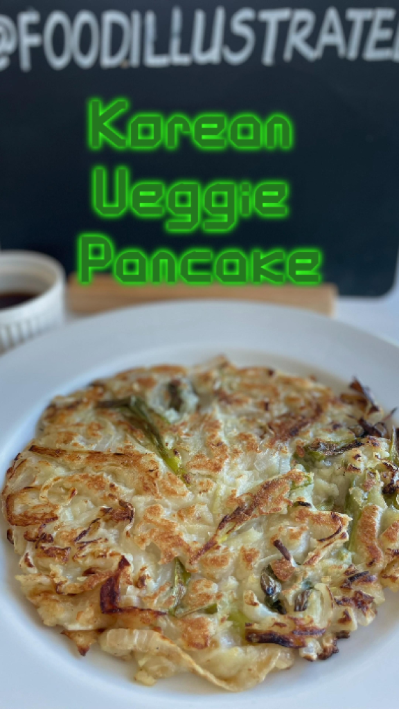 Crispy Korean vegetable pancake (yachaejeon) sliced into wedges on a wooden board with a small bowl of soy dipping sauce.