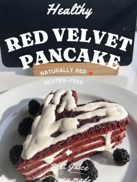 A tall stack of healthy red velvet pancakes cut into a perfect heart shape, topped with white cream cheese drizzle and fresh raspberries